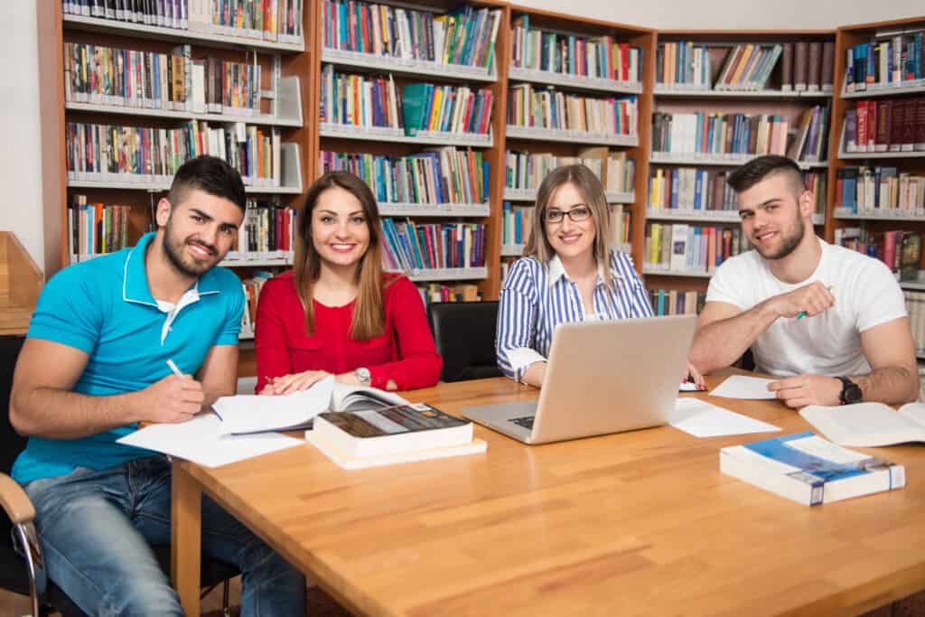 library handsome group students with laptop books working high school university library shallow depth field